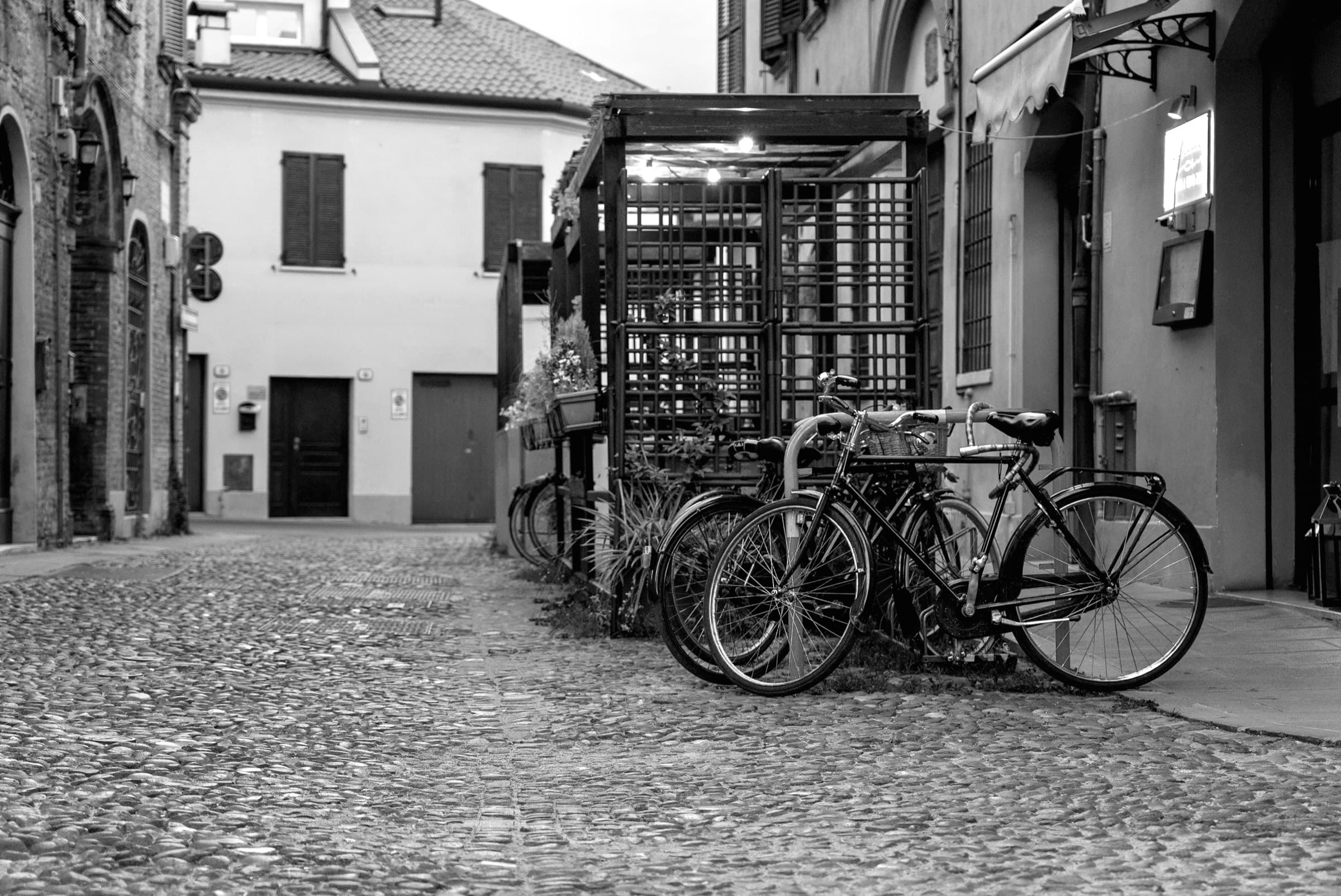 Fietsen voor het terras van Trattoria Le Nuvole, in zwart-wit